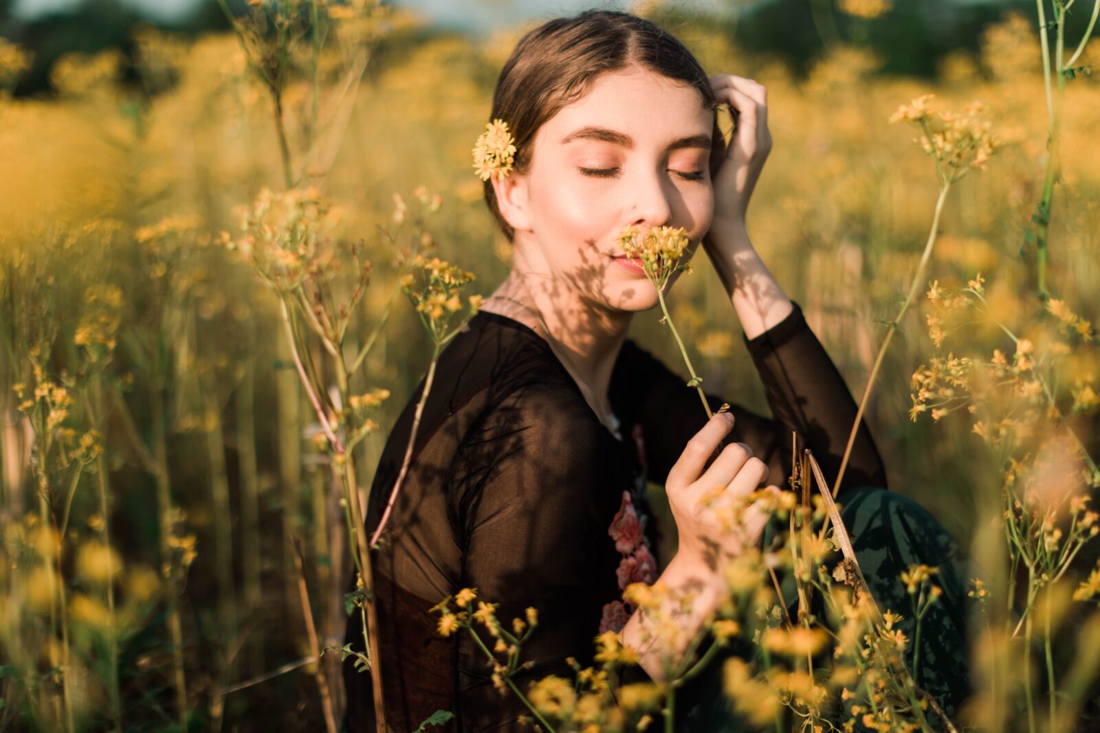 Lady in meadow smelling flowers