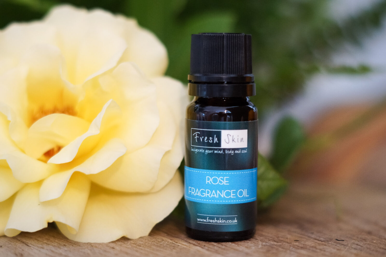 Rose Fragrance Oil bottle with rose in background