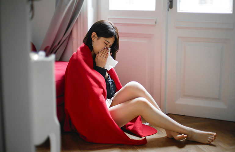Lady on floor sneezing into tissue